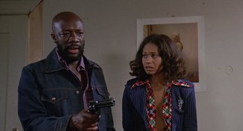 Movie still from “Truck Turner” (1974), directed by Jonathan Kaplan – A man and a woman holding a gun in a room; Medium shot, Low angle