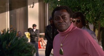 Movie still from “Truck Turner” (1974), directed by Jonathan Kaplan – A man wearing a pink sweater and a gold necklace; Close Up shot, Over the shoulder angle