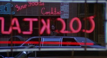 Movie still from “Truck Turner” (1974), directed by Jonathan Kaplan – A woman standing in front of a car in front of a building; Wide shot, Over the shoulder angle