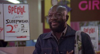 Movie still from “Truck Turner” (1974), directed by Jonathan Kaplan – A man with a beard is smiling for the camera; Close Up shot, Over the shoulder angle