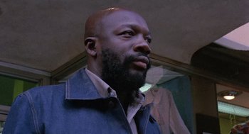 Movie still from “Truck Turner” (1974), directed by Jonathan Kaplan – A man with a beard is standing in front of a mirror; Close Up shot, Low angle