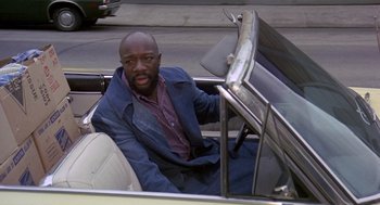 Movie still from “Truck Turner” (1974), directed by Jonathan Kaplan – A man sitting in the back seat of a convertible car; Medium shot, High angle