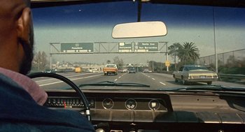 Movie still from “Truck Turner” (1974), directed by Jonathan Kaplan – A view from inside a car looking out the windshield of a car; Wide shot, High angle