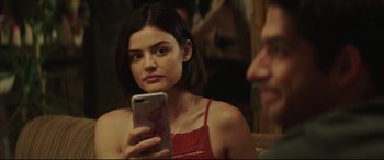 Movie still from “Truth or Dare” (2018), directed by Jeff Wadlow – A woman in a red top looking at a phone; Close Up shot, Over the shoulder angle