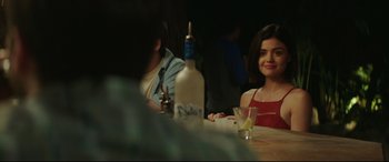 Movie still from “Truth or Dare” (2018), directed by Jeff Wadlow – A woman sitting at a table in front of a bottle of alcohol; Close Up shot, Over the shoulder angle