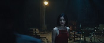 Movie still from “Truth or Dare” (2018), directed by Jeff Wadlow – A woman in a red dress standing next to a light; Medium shot, Over the shoulder angle