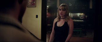 Movie still from “Truth or Dare” (2018), directed by Jeff Wadlow – A woman in a black tank top standing next to a door; Medium shot, Over the shoulder angle