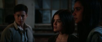 Movie still from “Truth or Dare” (2018), directed by Jeff Wadlow – A woman with short black hair is standing in front of a window; Close Up shot, Over the shoulder angle