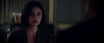 Movie still from “Truth or Dare” (2018), directed by Jeff Wadlow – A young woman is looking at the camera in a dark room; Close Up shot, Over the shoulder angle