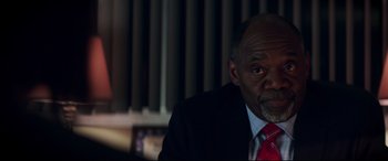 Movie still from “Truth or Dare” (2018), directed by Jeff Wadlow – A man wearing a suit and tie sitting in front of a curtain; Close Up shot, Over the shoulder angle