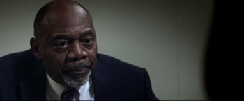 Movie still from “Truth or Dare” (2018), directed by Jeff Wadlow – An older man wearing a suit and tie looking at the camera; Close Up shot, Low angle