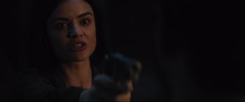 Movie still from “Truth or Dare” (2018), directed by Jeff Wadlow – A woman holding a gun in a dark room; Close Up shot, Over the shoulder angle