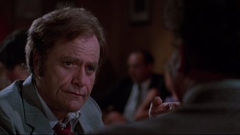 Movie still from “Twilight Zone: The Movie” (1983), directed by Steven Spielberg – A man in a suit and tie sitting at a table; Close Up shot, Over the shoulder angle