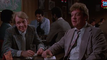 Movie still from “Twilight Zone: The Movie” (1983), directed by Steven Spielberg – A group of men sitting at a table with drinks; Medium shot, Over the shoulder angle