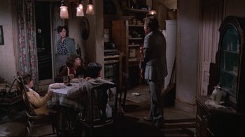 Movie still from “Twilight Zone: The Movie” (1983), directed by Steven Spielberg – A group of people sitting at a table in a room; Wide shot, Over the shoulder angle