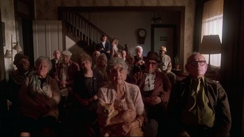 Movie still from “Twilight Zone: The Movie” (1983), directed by Steven Spielberg – An old woman sitting in front of a group of older people; Wide shot, High angle