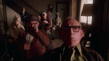 Movie still from “Twilight Zone: The Movie” (1983), directed by Steven Spielberg – A group of people sitting in a room; Medium shot, Low angle