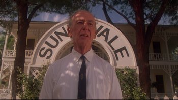Movie still from “Twilight Zone: The Movie” (1983), directed by Steven Spielberg – An older man wearing a tie standing in front of a building; Medium shot, Low angle