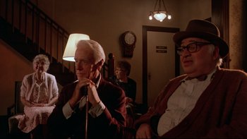 Movie still from “Twilight Zone: The Movie” (1983), directed by Steven Spielberg – An older man sitting next to another older man in front of a clock; Medium shot, Low angle