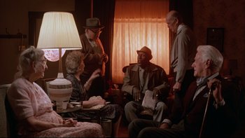 Movie still from “Twilight Zone: The Movie” (1983), directed by Steven Spielberg – A group of people sitting around a living room; Medium shot, Over the shoulder angle