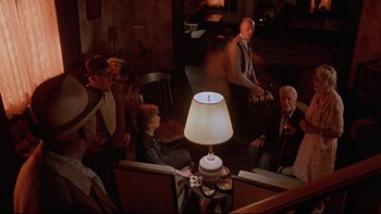 Movie still from “Twilight Zone: The Movie” (1983), directed by Steven Spielberg – A group of people sitting around a living room with a lamp; Wide shot, High angle