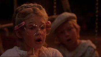 Movie still from “Twilight Zone: The Movie” (1983), directed by Steven Spielberg – Two young girls are dressed up and one of them is wearing glasses; Close Up shot, Over the shoulder angle