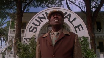 Movie still from “Twilight Zone: The Movie” (1983), directed by Steven Spielberg – A man standing in front of a building; Medium shot, Low angle
