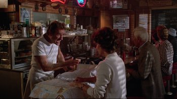 Movie still from “Twilight Zone: The Movie” (1983), directed by Steven Spielberg – A group of people sitting at a table in a restaurant; Medium shot, Over the shoulder angle
