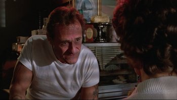 Movie still from “Twilight Zone: The Movie” (1983), directed by Steven Spielberg – A man sitting in front of a woman in front of a counter; Close Up shot, Over the shoulder angle