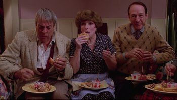 Movie still from “Twilight Zone: The Movie” (1983), directed by Steven Spielberg – A group of people sitting around a table with plates of food; Medium shot, High angle
