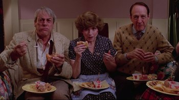 Movie still from “Twilight Zone: The Movie” (1983), directed by Steven Spielberg – A group of people sitting around a table with plates of food; Medium shot, High angle