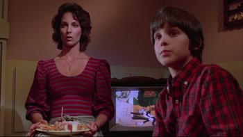Movie still from “Twilight Zone: The Movie” (1983), directed by Steven Spielberg – A woman and a boy in front of a television; Medium shot, Low angle