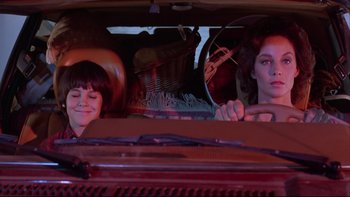 Movie still from “Twilight Zone: The Movie” (1983), directed by Steven Spielberg – Two people sitting in the back of a car; Medium shot, Over the shoulder angle