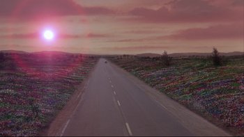Movie still from “Twilight Zone: The Movie” (1983), directed by Steven Spielberg – A car driving down a road near a field of flowers; Extreme Wide shot, High angle