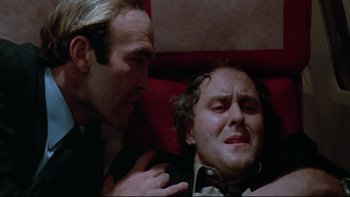 Movie still from “Twilight Zone: The Movie” (1983), directed by Steven Spielberg – A man crying next to another man on a couch; Close Up shot, Low angle