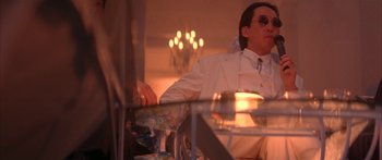 Movie still from “Twin Dragons” (1992), directed by Ringo Lam – A man sitting at a table in front of candles; Medium shot, Low angle