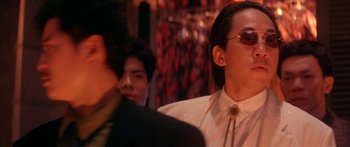 Movie still from “Twin Dragons” (1992), directed by Ringo Lam – A group of people standing next to each other in a room; Close Up shot, Low angle