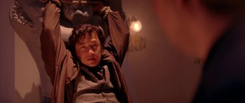 Movie still from “Twin Dragons” (1992), directed by Ringo Lam – A man sitting in a chair in a dark room; Close Up shot, Low angle
