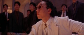 Movie still from “Twin Dragons” (1992), directed by Ringo Lam – A man with long hair wearing sunglasses and a white shirt; Close Up shot, Low angle