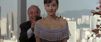 Movie still from “Twin Dragons” (1992), directed by Ringo Lam – A woman in a white dress is getting her picture taken by an older man; Medium shot, Low angle