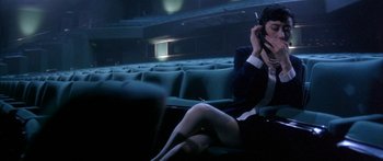 Movie still from “Twin Dragons” (1992), directed by Ringo Lam – A woman sitting on a chair talking on a cell phone; Medium shot, High angle
