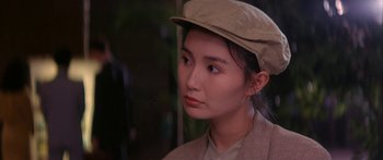 Movie still from “Twin Dragons” (1992), directed by Ringo Lam – A woman wearing a tan hat looking to her left; Close Up shot, Over the shoulder angle