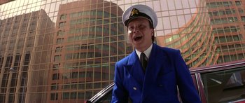 Movie still from “Twin Dragons” (1992), directed by Ringo Lam – A man in a blue suit and a white hat is smiling; Medium shot, Low angle