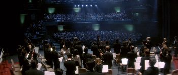 Movie still from “Twin Dragons” (1992), directed by Ringo Lam – A crowd of people in a large auditorium with musical instruments; Extreme Wide shot, High angle