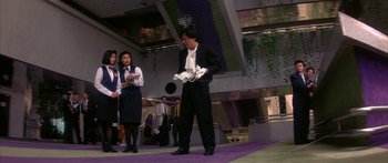 Movie still from “Twin Dragons” (1992), directed by Ringo Lam – A man in a suit and tie holding a white object; Wide shot, Low angle
