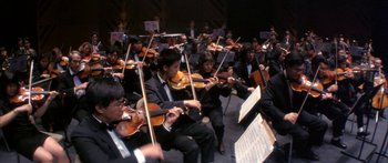 Movie still from “Twin Dragons” (1992), directed by Ringo Lam – A group of people in black suits playing musical instruments; Wide shot, Low angle