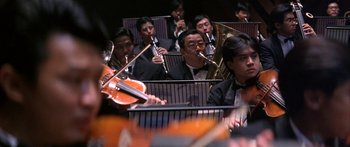 Movie still from “Twin Dragons” (1992), directed by Ringo Lam – A group of men in suits playing musical instruments in an orchestra; Medium shot, Low angle