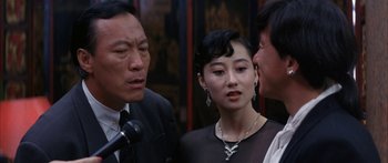 Movie still from “Twin Dragons” (1992), directed by Ringo Lam – A man and two women standing next to each other; Close Up shot, Over the shoulder angle