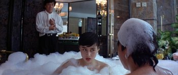 Movie still from “Twin Dragons” (1992), directed by Ringo Lam – A woman sitting in a bath tub surrounded by foam; Medium shot, Over the shoulder angle