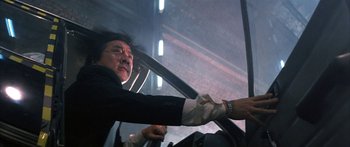 Movie still from “Twin Dragons” (1992), directed by Ringo Lam – A man in a suit and tie holding onto a car window; Medium shot, Low angle